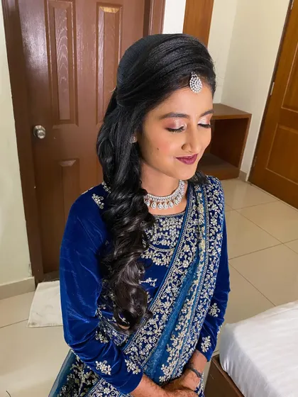 A glamorous reception look with side-swept curls and a neat puff at the crown, perfect for showcasing a maang tikka.