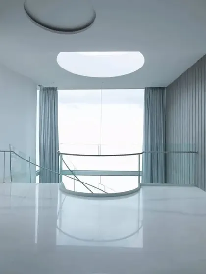 A serene, minimalist space featuring a circular skylight and floor-to-ceiling grey curtains, demonstrating how emptiness and light can be used to create a sense of calm and inertia.