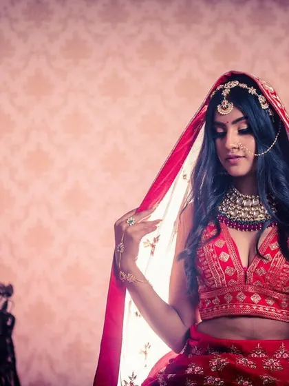 A full-body shot with a dramatic feel. The bride is posed with her red veil, creating a powerful and traditional bridal image.