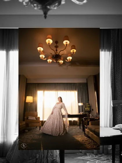 An artistic, color-splashed black and white photo of the bride in her reception gown, standing under a grand chandelier.