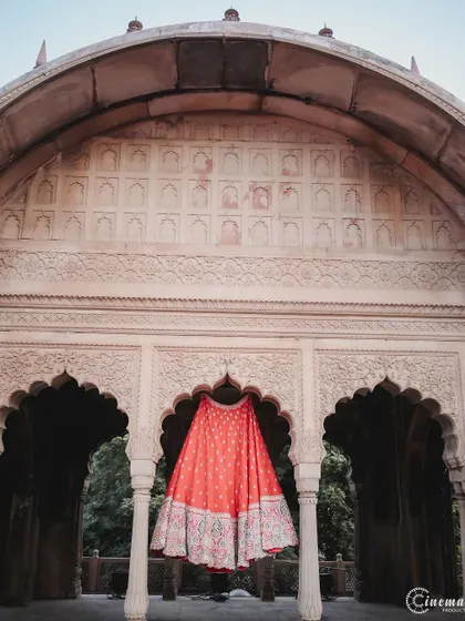 A creative shot of the bride's lehenga skirt hanging in a beautiful archway, highlighting the outfit as a piece of art.