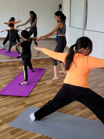 Guiding my young students in Warrior II pose. I focus on helping them find the right alignment in a way that feels empowering, building strength and stability.