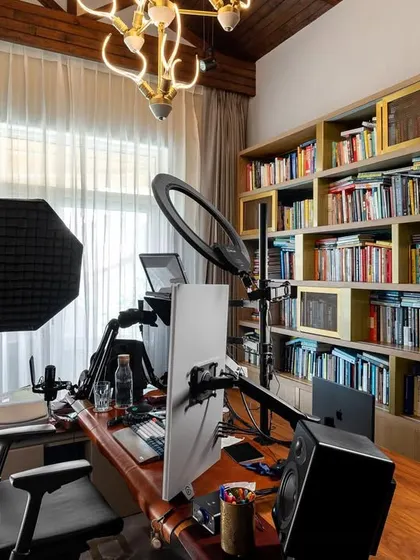 A personalized home office and podcasting studio designed for our client at the Amara residence. The space features a large bookshelf, professional recording equipment, and a warm, inviting atmosphere for creative work.