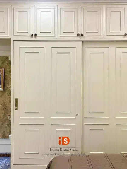 The elegant floor-to-ceiling wardrobes with a white Duco finish and classic hardware, providing ample storage while enhancing the room's sophisticated English style.