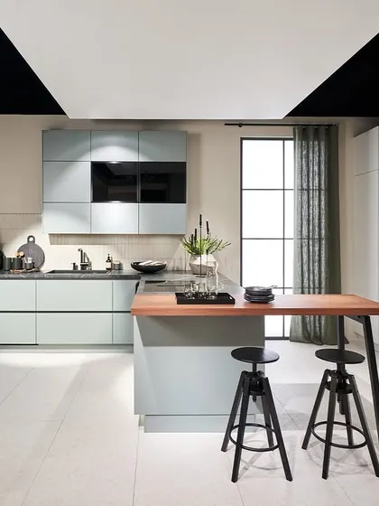 This kitchen from our 2025 novelties collection features a soft, dusty blue-green finish, paired with a wood-topped island and a built-in wine rack.