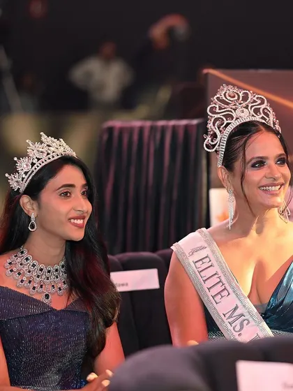 A candid moment of two beauty queens enjoying the show. These behind-the-scenes glimpses add a human touch to the glamour.