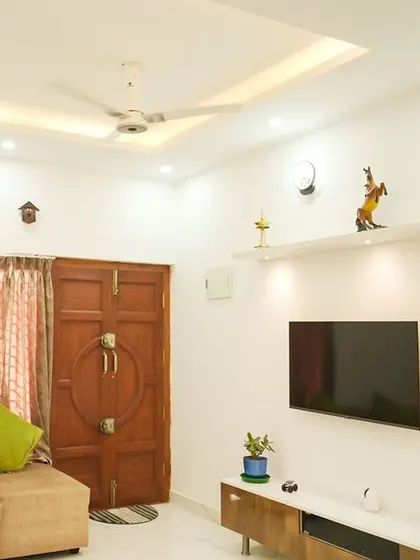 A minimalist living room with floating shelves above the TV for display. The simple wooden console and neutral tones create a calm and inviting atmosphere.
