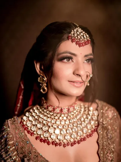 A close-up portrait showcasing the soft smokey eye and perfectly defined features, paired with a stunning ruby necklace.