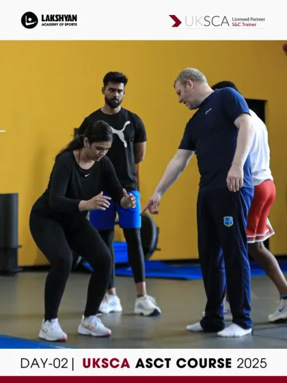A UKSCA trainer provides one-on-one correction on squat form. This personalized feedback during Day 2 ensures participants master foundational movements before assessment.
