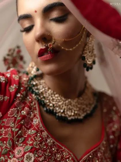 A close-up editorial portrait of a model as an Odia bride. The focus is on her bold red lip, traditional jewelry, and the delicate veil, creating a powerful and beautiful image.