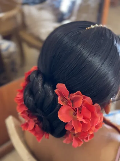 A classic bridal bun adorned with bright red flowers, a bold and beautiful choice for a bride.