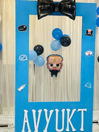 A fun photo booth frame for a Boss Baby party. The blue frame is personalized with the name "AVYUKT" and decorated with themed stickers.