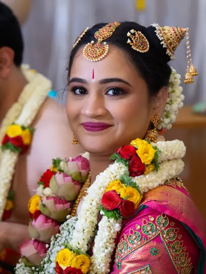 A close-up of Vibha's radiant Muhurtham look. The makeup is designed to complement the vibrant colors of her saree and the intricate details of her floral garland.