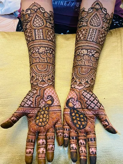 This design highlights the beauty of the peacock, with large, detailed peacock figures on the palms and smaller elephant motifs on the fingers.