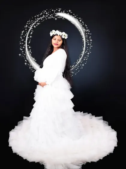 This white ruffle gown with a long trail is a classic and angelic choice for a studio maternity photoshoot.