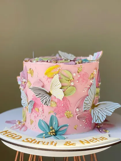 A beautiful pink cake with a painted buttercream effect, adorned with delicate wafer paper butterflies and gold leaf. This design is perfect for a spring or summer birthday.