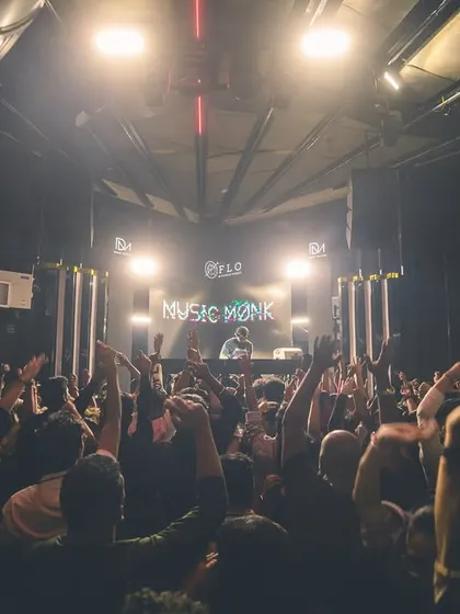 The crowd's hands are up as my logo glows from the stage. A classic view from the DJ booth, capturing the energy of a packed venue.