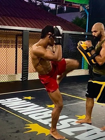 Step by step, we build a fighter. A student practicing a knee strike on the pads, a crucial weapon in Muay Thai and MMA.