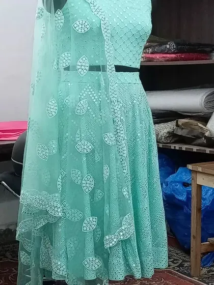A studio shot of the mint green mirror work lehenga, showing the detail on the net dupatta and the intricate pattern on the skirt and blouse.
