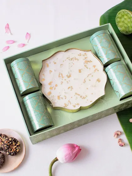 A luxe hamper featuring a large Urli candle and four tins of our best savory and sweet snacks, including Sichuan Peanut Crunch and Fruit & Nut Clusters.