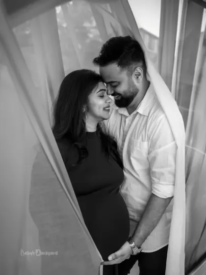 Wrapped in a soft curtain of light, this couple shares a private, loving moment. Our black and white couple portraits are perfect for creating timeless, emotional keepsakes of your pregnancy journey.