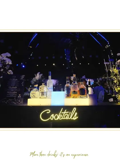 A sleek and modern cocktail bar with a neon sign and a full display of premium spirits. This setup is versatile and can be adapted for any high-energy party or reception.