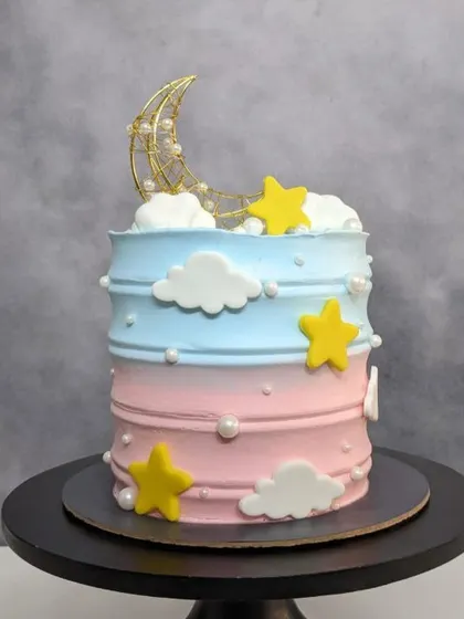 A tall and beautiful baby shower cake with a moon and stars theme, in soft pink and blue. Swipe to see the surprise.