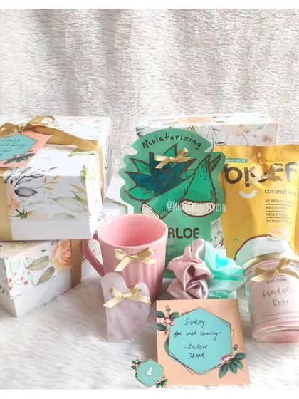 The contents of the "Sorry for not coming" hamper. It includes a face mask, a scented candle, a cute mug, and scrunchies to send a little bit of pampering and love.