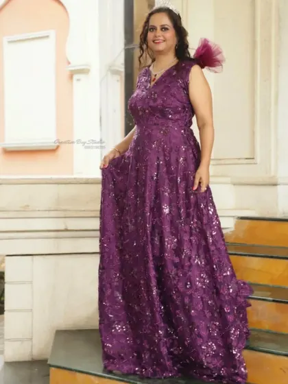 This dark purple gown with stone work is a simple yet elegant option for an evening party. The one-shoulder ruffle detail adds a modern touch.