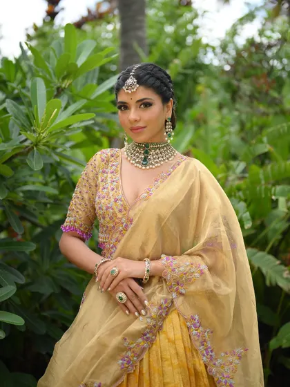 A full view of the gold and purple half saree, featuring a Kanchipuram silk lehenga and a tissue dupatta with floral embroidery.