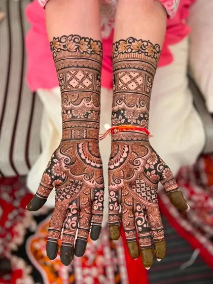 This intricate design combines floral bands with geometric patterns for a balanced and beautiful bridal look. The dark fingertips are a classic bridal touch.