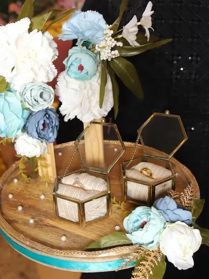 Our custom-designed engagement ring platter for Arpita and Akshay. The rustic wooden platter is adorned with floral arrangements in shades of blue and white, and features two beautiful glass and brass hexagonal boxes to hold the rings.