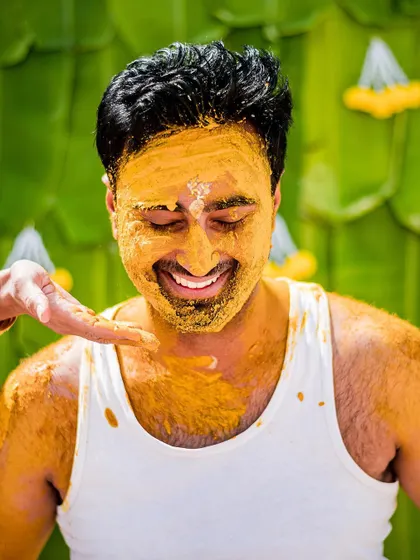 The groom's playful smile as turmeric paste is applied to his face during the Haldi ceremony. We capture the fun and candid moments that make each wedding unique.