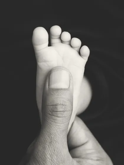 This black and white version emphasizes the contrast in size and the delicate perfection of a newborn's foot. It's a simple, yet profound, image.