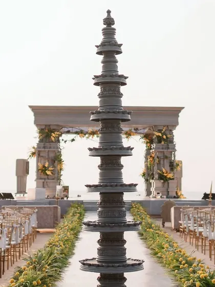A traditional brass lamp stands tall, marking the entrance to the grand beachside mandap. This element grounds the modern setup in rich cultural heritage, blending old and new.