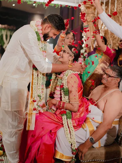 The groom blesses his bride with sacred rice during Suhaashini and Preetham's wedding. The presence of family members makes this traditional moment even more special.