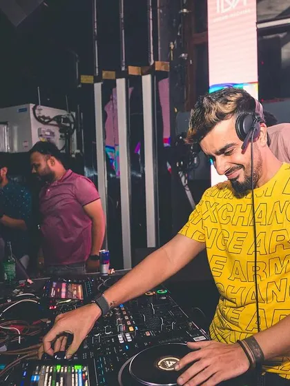 A candid shot of me smiling while mixing on the vinyl turntables. I enjoy every second of my work, and I think it shows.