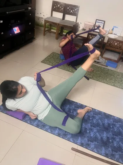 Two clients use straps for a deep, restorative leg and hip stretch.