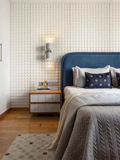 For this compact bedroom, we leaned into its cozy size to create a snug atmosphere. The highlight is the striking headboard wall, where a white checkered panel adds texture and visual interest, complemented by a rich blue fabric headboard for depth and sophistication.