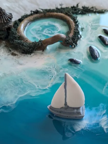 A complete view of the charming resin ocean diorama, featuring a sailboat, a small island, and stepping stones.