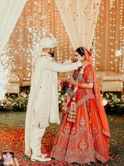 A beautiful moment during the Varmala ceremony, with the groom placing the garland on his bride, surrounded by sparklers.