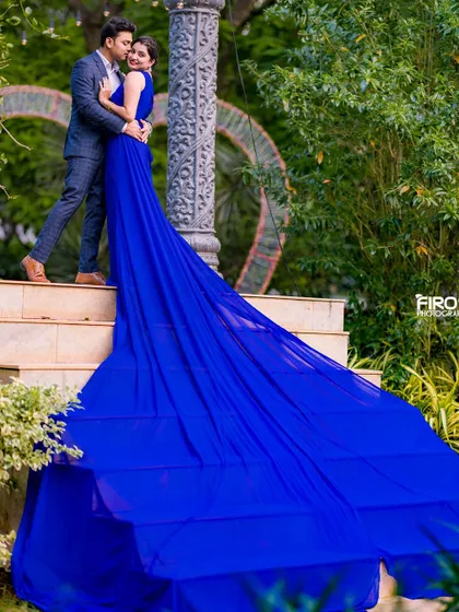 A close-up of a romantic moment on the steps. The groom-to-be whispers to his partner, while the dramatic blue gown flows down, creating a beautiful and intimate scene.