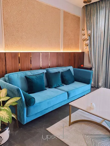 A bright velvet cobalt sofa adds a splash of color to this bedroom's seating area. The bold color is balanced by shimmery powder blue curtains and neutral wall panels.