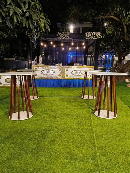 A stylish bar setup for an outdoor cocktail night, with modern high-top tables and warm overhead lighting.