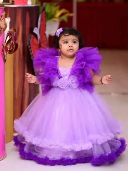 A close-up of the birthday girl in her butterfly-themed dress. The dress has a dramatic ruffled collar made of dark purple tulle.
