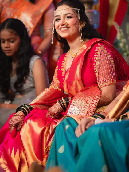 A candid shot of a Maharashtrian bride smiling during her wedding events, looking absolutely radiant in her red saree.