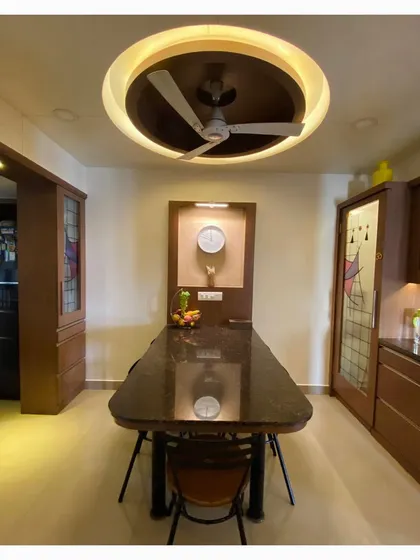 The dining area is designed for family gatherings, with a durable granite table and a unique circular ceiling feature that mirrors the shape of a traditional dining setting. Stained glass details on the cabinetry add a personal touch.