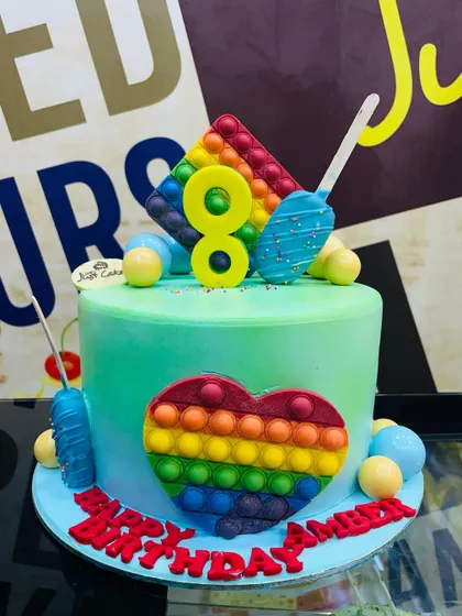 A colorful 2kg Pop It cake for an 8th birthday, with a heart and star-shaped fondant Pop It design.
