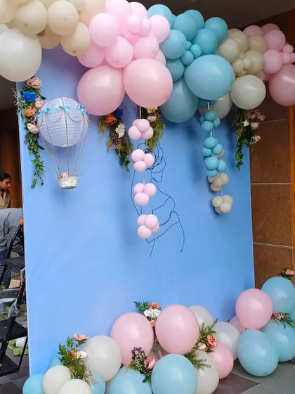 Another angle of the 'He or She?' baby shower decor, showing the hot air balloon prop and floral details.