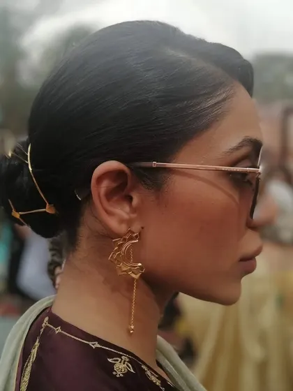A sleek and modern updo, accessorized with a unique gold hairpiece. This is a great way to add a contemporary touch to a traditional outfit.
